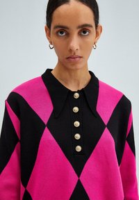 Maglione lavorato a maglia in nero e rosa con un motivo a rombi. Presenta un colletto e cinque bottoni dorati lungo il davanti. Tessuto testurizzato.