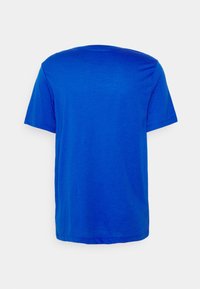 Camiseta de cuello redondo de manga corta azul sólido, mostrada por la parte de atrás sobre un fondo blanco.