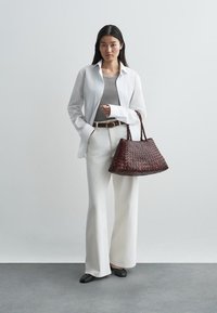 Υφασμένη μπορντώ τσάντα, λευκό πουκάμισο, γκρι μπλούζα, λευκά παντελόνια, φαρδιά leg, μαύρες φλατ; λεία υφή, χαλαρός σχεδιασμός, ουδέτερα χρώματα.