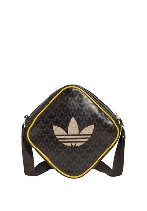 Sac à bandoulière carré noir avec bordure jaune, motif logo répétitif, et grand logo beige en forme de trèfle à l'avant, avec une sangle sombre réglable.