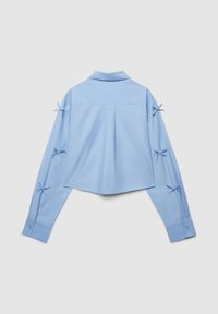 Hellblaues kurz geschnittenes Hemd mit Kragen, langen Ärmeln und Schleifenakzenten an den Ärmeln. Glatter Stoff und strukturiertes Design.