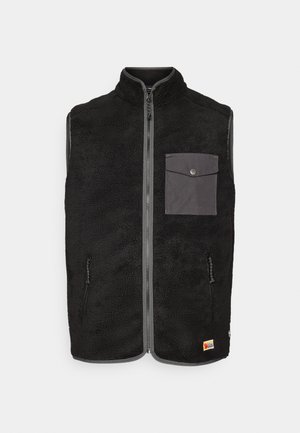 Zwart fleece mouwloos vest met een ritssluiting aan de voorkant, grijze flapborstzak, twee ritszakken aan de zijkant, en een klein logo-embleem aan de onderrand.