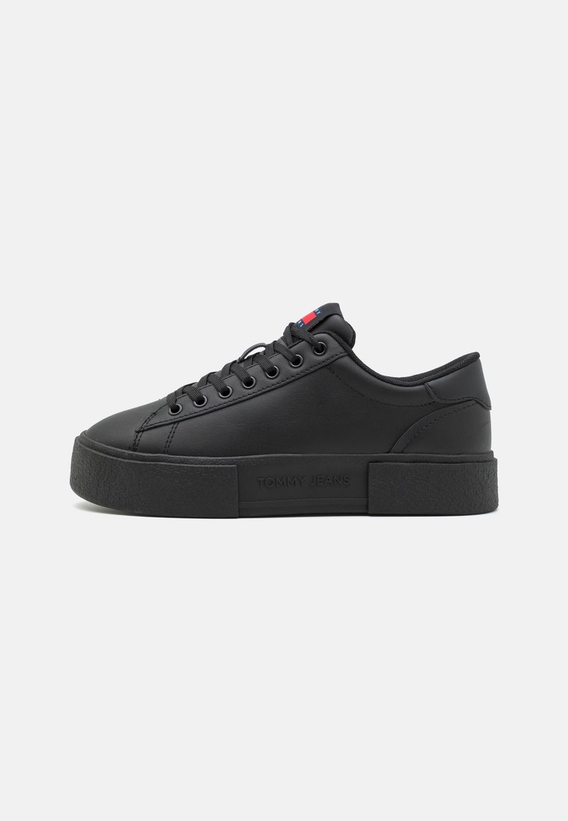 Basket basse noire avec semelle épaisse, design lacé et petit détail de drapeau rouge, blanc et bleu sur la languette, embossé "Tommy Jeans" sur le côté.