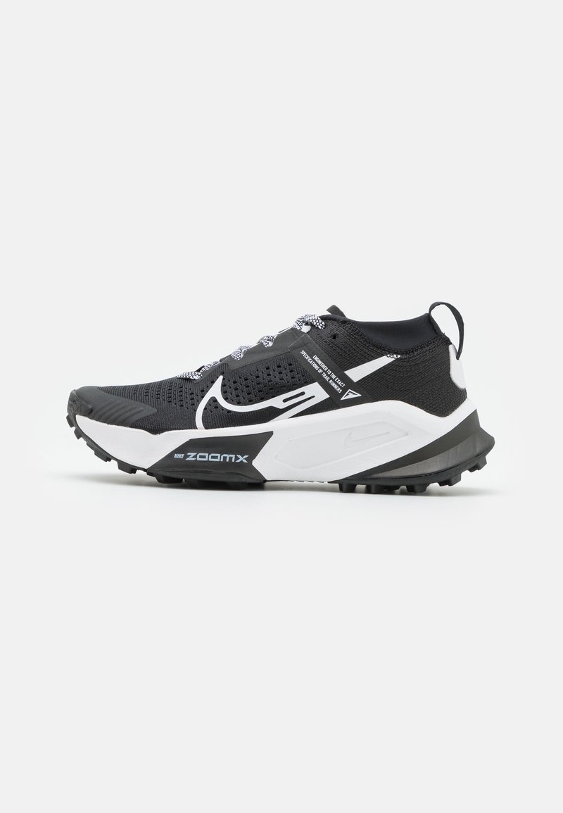 Chaussure de sport noir et blanc avec un dessus en maille texturée, un talon renforcé, des accents réfléchissants et une semelle extérieure robuste pour l'adhérence.