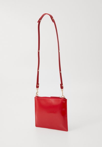 Röd lädercrossbody-väska med en slät yta, rektangulär form, justerbar rem och guldiga detaljer.