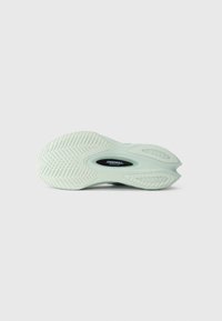 Semelle de chaussure de sport vert clair avec caoutchouc texturé, présentant un motif de semelle distinct et un insert étiqueté "TECHNOLOGIE SPEEDROLL".