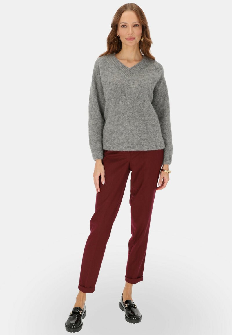 Szary, puszysty sweter v-neck w połączeniu z bordowymi spodniami węższymi w kostkach. Czarne mokasyny dopełniają stylizację. Miękka tekstura z podwiniętymi spodniami dla swobodnego wyglądu.