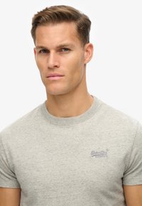 T-shirt in cotone grigio con maniche corte, collo a giro e logo ricamato sul petto. Tessuto liscio con una vestibilità classica.