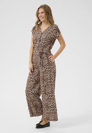 Tuta con stampa leopardata, maniche corte, scollatura a V, vita con cintura, gambe larghe e tessuto leggero. Indossato con scarpe nere basse.