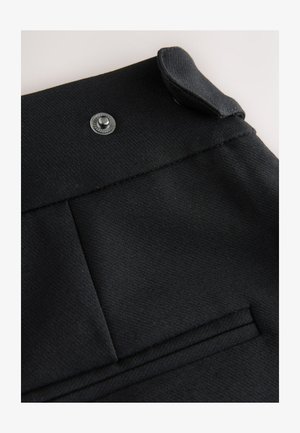 Zwarte stof met een gladde textuur, voorzien van een bovenste knoop en een decoratieve klep. Bevat een horizontale zak met gestikte details.