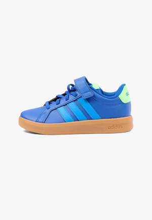 Baskets Adidas bleues avec semelle en gomme, trois bandes bleues, lacets et bride à velcro, et languette de talon vert néon sur fond blanc.