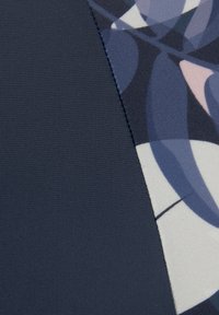 Tissu multi-texturé présentant une section bleu foncé et une zone à motifs avec des courbes douces dans des teintes de bleu, rose et crème.