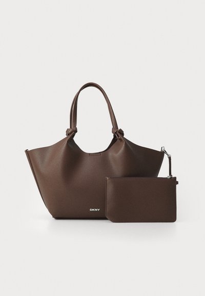Sac en cuir brun texturé avec des poignées nouées et une pochette zippée assortie, tous deux arborant le logo argenté de DKNY.