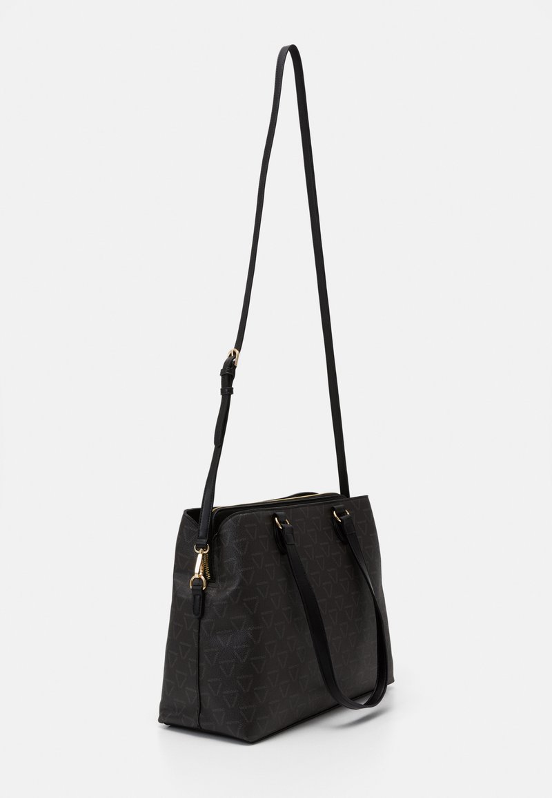 Bolso tote negro hecho de material texturizado con un patrón geométrico. Cuenta con un zipper dorado, doble asa y una correa larga ajustable.