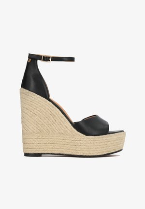 Sort læder kilehælssandal med åben tå, juteropes detalje på kilehælen og en justerbar ankelrem. Den samlede højde er betydelig.