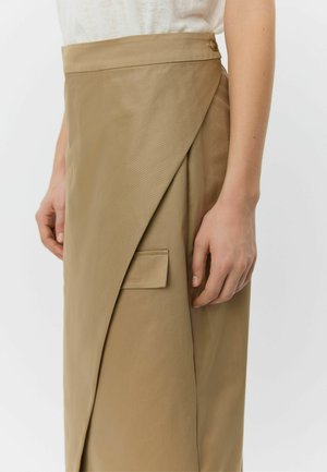 Beige wikkelrok van gladde stof, met een asymmetrisch ontwerp, zijzak en een knoopdetail aan de tailleband.