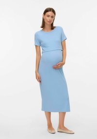 Robe midi côtelée bleu clair avec des manches courtes, corsage ajusté et jupe évasée, accessoirisée avec des ballerines beiges. Texture lisse.