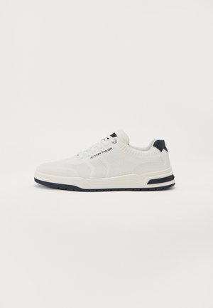 Witte sneakers met een gebreide textuur, voorzien van een marineblauw accent op de hiel en zool. Platte veters en een afgeronde neusontwerp.