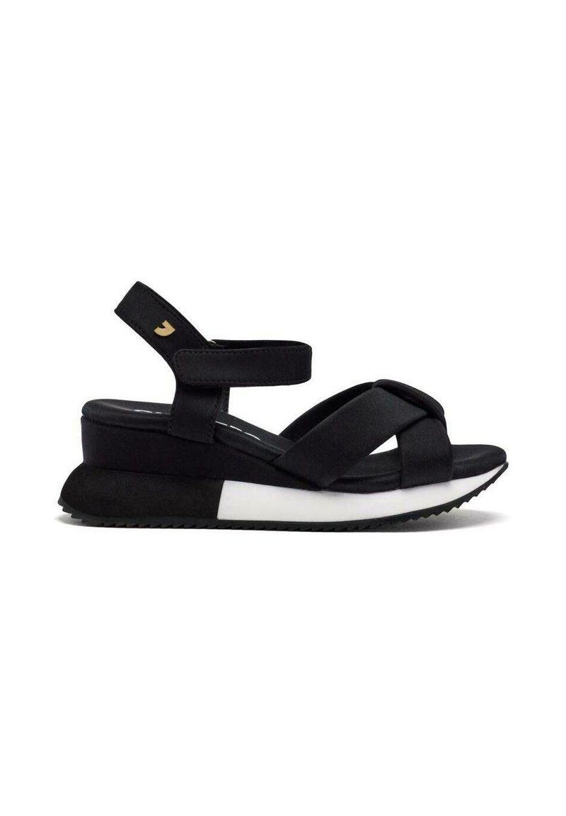 Sandalias de plataforma negras con una parte superior de tejido texturizado, diseño de tira cruzada, correa ajustable en el tobillo y suela ligera blanca y negra.