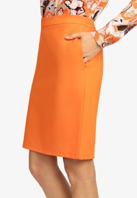 Väriä orange oleva kynähame, joka on valmistettu sileästä materiaalista. Hameessa on kapea istuvuus, sivutaskut, siisti helma ja ei havaittavia kuvioita.