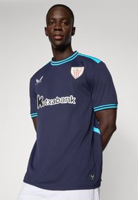 Maillot de sport bleu marine avec des accents turquoise, présentant un col rond, des manches courtes et une impression de logo et de sponsor à l'avant.