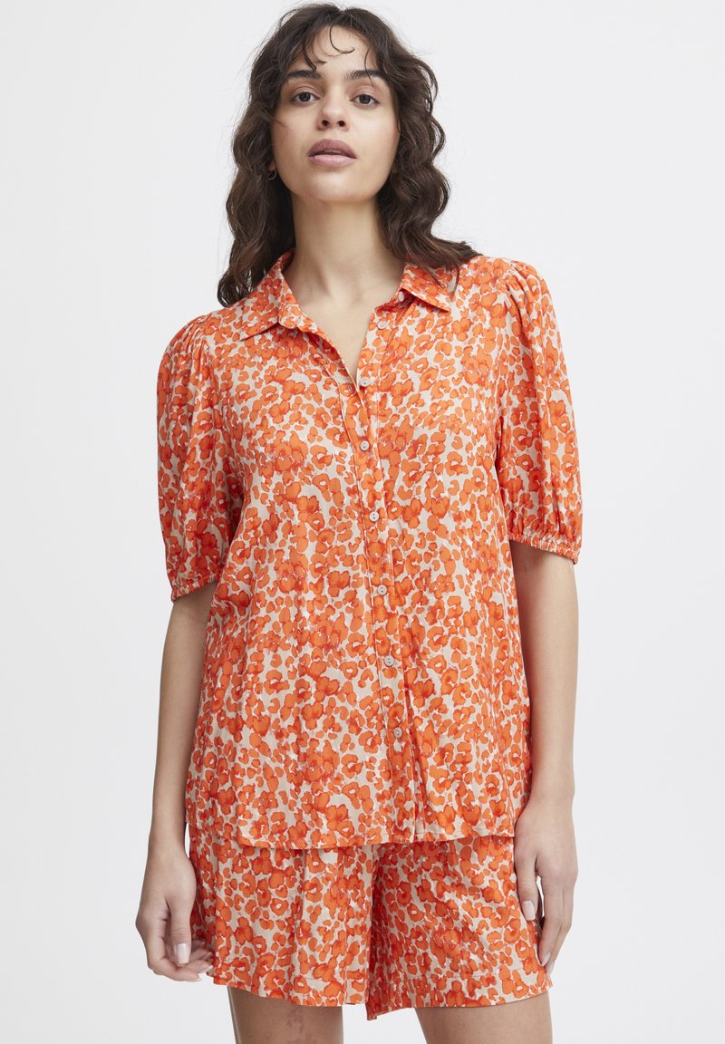 Orange button-up shirt and matching shorts with a floral pattern. Short puff sleeves, lightweight fabric, and a relaxed fit design.