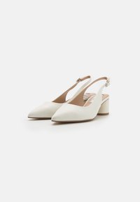 Talons hauts slingback en cuir blanc avec des bouts pointus, un petit talon bloc et une bride adjustable à la cheville. Texture lisse avec des accents minimalistes.