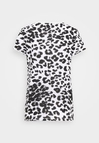 Chemise blanche à manches courtes avec motif léopard noir irrégulier, vue de dos sur un fond uni.