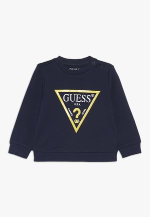 Sudadera azul marino de algodón, con un logo triangular dorado que incluye el texto "GUESS U.S.A." y un signo de interrogación en el centro.
