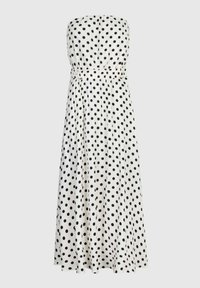 Robe blanche sans manches avec des pois noirs, dotée d'une taille élastiquée et d'une jupe fluide pour un ajustement décontracté. Texture de tissu lisse.
