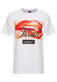 Wit T-shirt met een grote afbeelding van rode lippen en gouden accenten, met de tekst "Thrills" in zwart en "Mister Tee" in een klein label eronder.