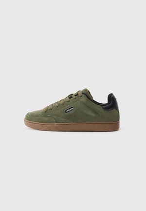 Low-top olive green suede sneaker with brown sole, round toe, lace-up closure, and black padded heel collar.