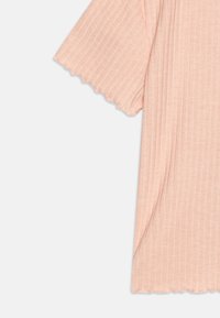Top rosa claro canelado com mangas em padrão de onda, apresentando uma textura suave e um corte descontraído. Sem padrões proeminentes ou detalhes em metais.