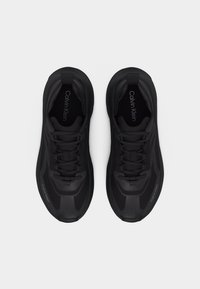 Paire de baskets à lacets Calvin Klein noires vues de dessus sur fond blanc.