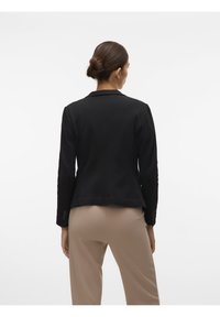 Zwarte blazer met een getailleerde pasvorm, lange mouwen en een reverskraag met inkeping. Heeft knoopaccenten op de mouwen en een gladde, matte textuur.