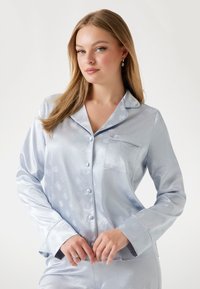 Ensemble de pyjama en satin bleu clair avec un motif de roses, doté d'un col à revers, d'une fermeture à boutons et de manches longues. Légère brillance et détail de poche.