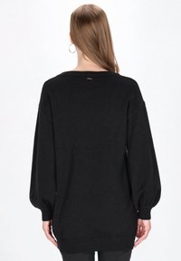 Schwarzer Pullover mit lässiger Passform, überschnittenen Schultern, Ballonärmeln und gerippten Bündchen. Verfügt über einen runden Halsausschnitt und dezenten Markenaufdruck.