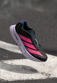 Schwarzer Laufschuh mit pinkfarbenen Streifen, violetten Akzenten und einer leichten Sohle. Atmungsaktives Mesh-Obermaterial mit strukturierter Oberfläche.