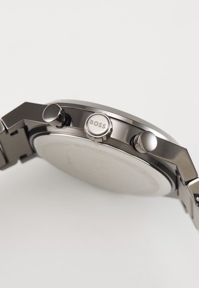 Montre pour homme en acier inoxydable avec un cadran rond, finition argentée, deux boutons-poussoirs et une couronne gravée "BOSS." Surface lisse et polie.