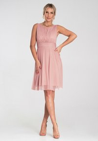 Jasnoróżowa sukienka bez rękawów z marszczonym korpusem, zwiewną spódnicą z chiffon oraz delikatnymi detalami w pasie. Gładka tekstura, o długości do kolan.