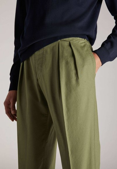 Olivgrüne, plissierte Hose mit lockerer Passform und Seitentaschen, kombiniert mit einem marineblauen Pulli. Geschmeidige Stofftextur, lässiges Design.