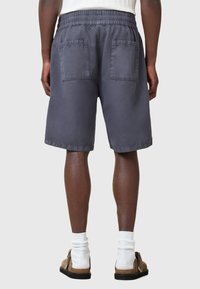 Pantaloni shorts in cotone grigio scuro con una vestibilità rilassata, caratterizzati da un elastico in vita e due tasche applicate sul retro.
