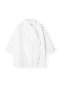 Camicetta bianca a maniche corte con un design frontale asimmetrico unico, colletto piegato e chiusura con bottone, realizzata in tessuto leggero.