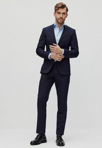 Marine blazer met bijpassende broek, lichtblauw shirt en zwarte dresschoenen. Glad stof en verfijnde pasvorm.