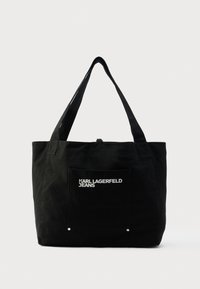 Čierna plátenná taška cez rameno s dvoma ramennými popruhmi, predným vreckom s bielym logom "KARL LAGERFELD JEANS", jednoduchý dizajn bez viditeľných zapínaní.