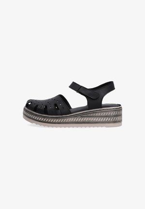Sorte platform sandaler med udskæringsdesign og rem, der fremviser en struktureret sål og dekorativ syning omkring bunden.