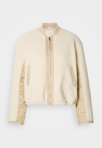 Μπουφάν τύπου μπομπονιέρα σε κρεμ απόχρωση με αφράτη εξωτερική επιφάνεια, ταμπά καπιτονέ μανίκια, ριμπ γιακά και δύο πλαϊνές τσέπες. Κλείνει μπροστά με φερμουάρ.