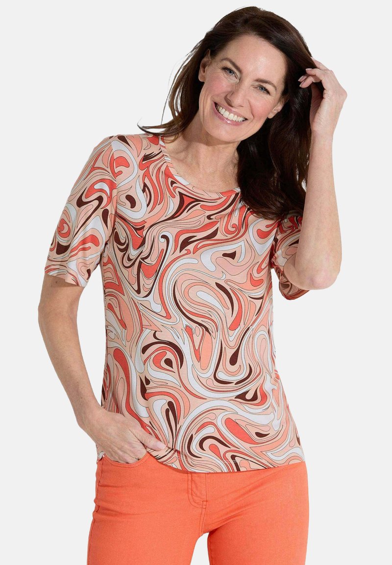 Korte mouw t-shirt in een spiraalpatroon van koraal, bruin en crème kleuren; zachte stof, ronde halslijn, losse pasvorm.