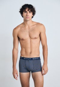 Boxers en jersey marine avec un motif géométrique doré. Tissu doux, taille élastique avec le logo "GANT", et design ajusté.