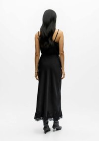 Robe maxi en satin noir avec bretelles spaghetti et ourlet bordé de dentelle, présentant une silhouette élégante et fluide ainsi qu'une texture lisse.